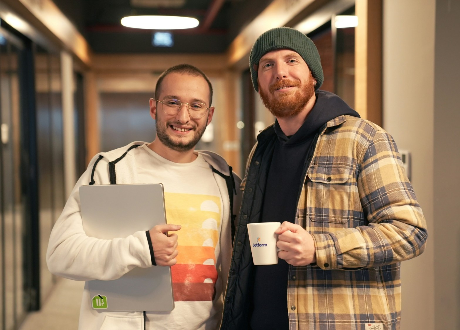 two men looking at the camera smiling in a workplace